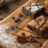 Gooey homemade brownies recipe with cracked tops and chocolate drizzle on a wooden board