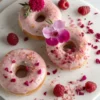 Freshly made hibiscus glazed donuts topped with floral garnishes and raspberries – a sweet floral treat